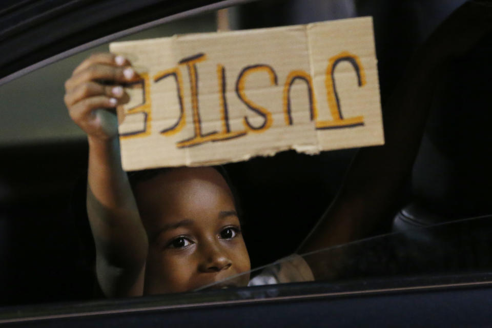 FILE - This photo from Sunday May 31, 2020, shows A youngster holding a "Justice" sign upside down, as he peers outside the window of a car passing protesters in Richmond, Va. The chaos unleashed in 2020, amid the coronavirus pandemic, has created space for different voices to speak, for different conversations to be had and for different questions to be asked. (AP Photo/Steve Helber, File)