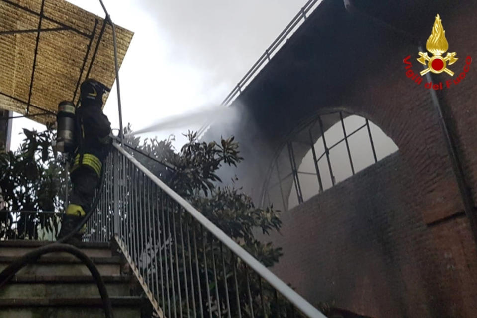 A firefighter puts out a fire at the Cavallerizza Reale, royal stables part of a UNESCO World Heritage site in the center of Turin, Monday, Oct. 21, 2019. (Vigili del Fuoco via AP)