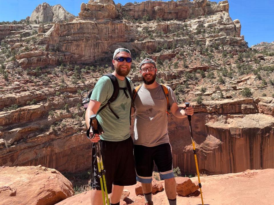 timothy moore and husband trent standing on hike with poles with rock formation behind