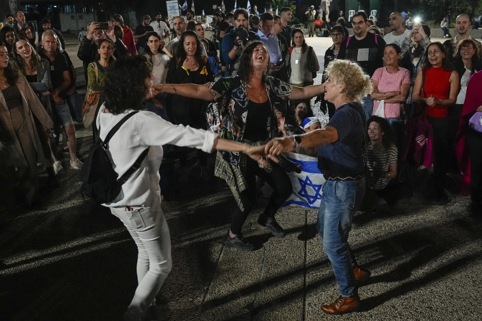 People react as they hear the news of the release of 13 Israeli hostages held by Hamas in the Gaza strip, in Tel Aviv, Israel, on Friday, Nov. 24, 2023. Friday marks the start of a four-day cease-fire in the Israel-Hamas war, during which the Gaza militants pledged to release 50 hostages in exchange for 150 Palestinians imprisoned by Israel. (AP Photo/Ariel Schalit)