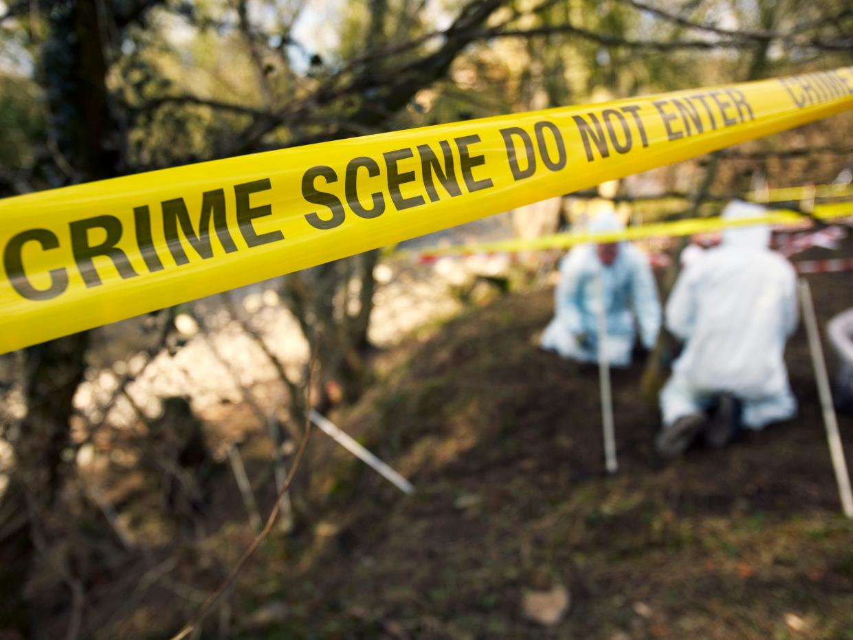 stock image of crime scene tape and investigators