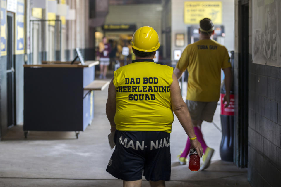 Marty Jones, one of the original members of the Savannah Bananas' Man-Nana Dad Bod Cheerleading Squad, walks beneath the stadium after a meeting before the team's game against the Florence Flamingos, Tuesday, June 7, 2022, in Savannah, Ga. (AP Photo/Stephen B. Morton)