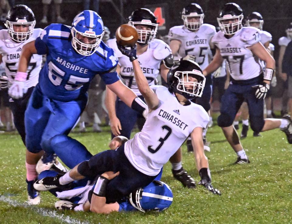 Thomas Hansen of Cohasset tosses the ball out of bounds as he is brought down by Brian Neves and Mason Zylinski (55) of Mashpee.