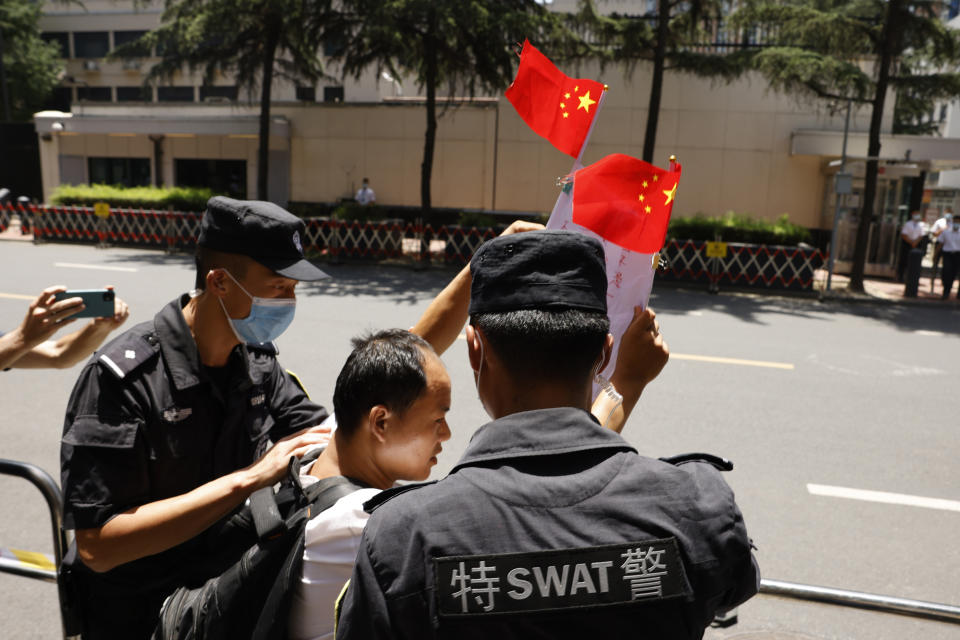A Chinese man is taken away after shouting pro-China slogans outside the former United States Consulate in Chengdu in southwest China's Sichuan province on Monday, July 27, 2020. Chinese authorities took control of the former U.S. consulate in the southwestern Chinese city of Chengdu on Monday after it was ordered closed amid rising tensions between the global powers. (AP Photo/Ng Han Guan)