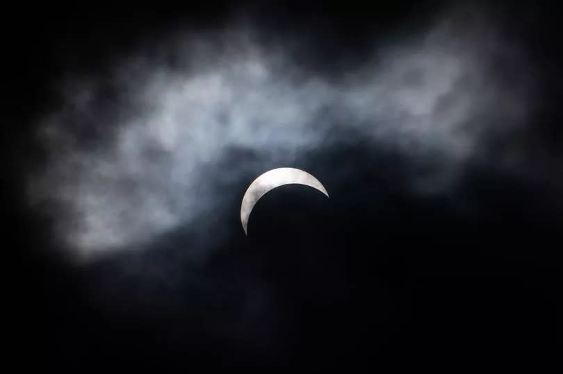 The solar eclipse is seen through the clouds  in Niagara Falls
