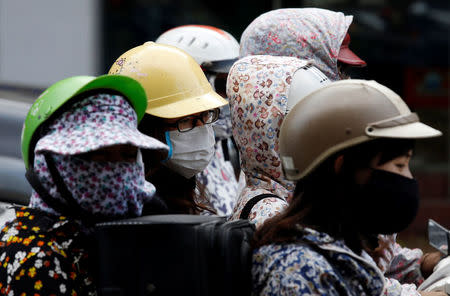 People wear protective masks while riding on a street in Hanoi, Vietnam May 21, 2018. Picture taken May 21, 2018. REUTERS/Kham