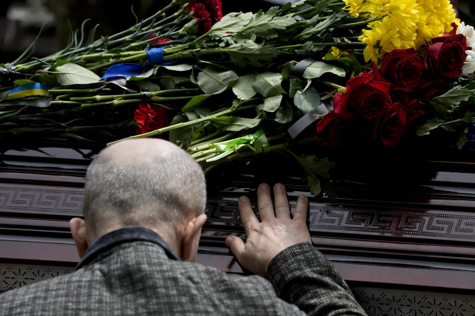 A man touches the coffin with the remains of activist and soldier Roman Ratushnyi during his funeral in Kyiv, Ukraine, Saturday, June 18, 2022. Ratushnyi died in a battle near Izyum, where Russian and Ukrainian troops are fighting for control of the area. (AP Photo/Natacha Pisarenko)