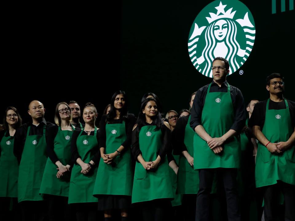 Starbucks baristas standing up. Strategy chief aims to increase dialogue with Starbucks baristas as CEO seeks to head off unions.