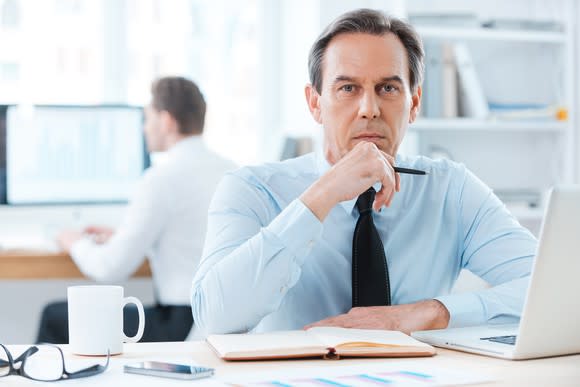 A baby boomer in deep thought in front of his laptop.