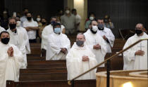 In this photo taken Saturday, June 20, 2020, priests from the Rio Grande Valley wear face masks against the spread of the coronavirus as they attend a Priestly Ordination Ceremony at the Basilica of Our Lady of San Juan Del Valle in San Juan, Texas. (Delcia Lopez/The Monitor via AP)