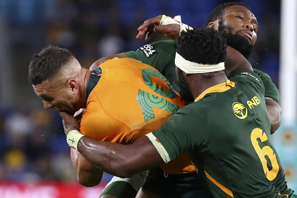 Australia's Quade Cooper, left, is wrapped up by South Africa's Siya Kolisi and Lukhanyo Am, right, during their Rugby Championship match on Sunday, Sept. 12, 2021, Gold Coast, Australia. (AP Photo/Tertius Pickard)