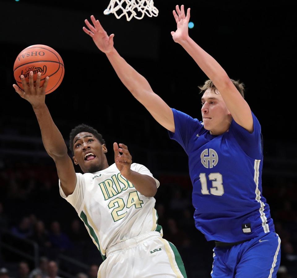 St. Vincent-St. Mary guard Sencire Harris, left, makes a layup under Gilmour Academy forward Ryan Mueller during the second half of the Division II state championship Sunday at the University of Dayton Arena.  STVM won 63-35. [Jeff Lange/Beacon Journal]
