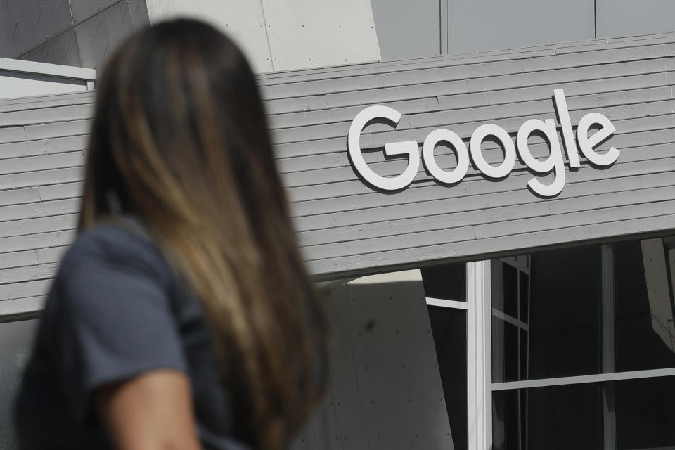 FILE - In this Sept. 24, 2019, file photo a woman walks below a Google sign on the campus in Mountain View, Calif. Five technology giants reported mixed earnings results Thursday, Oct. 29, 2020 a sign of varying fortunes as they try to rebound from an pandemic-related economic slowdown earlier this year. While all five — Amazon, Google parent Alphabet, Facebook, Apple and Twitter — exceeded analyst expectations, gloomy forecasts and other uncertainties led to share-price declines for all but Alphabet in after-market trading. (AP Photo/Jeff Chiu, File)