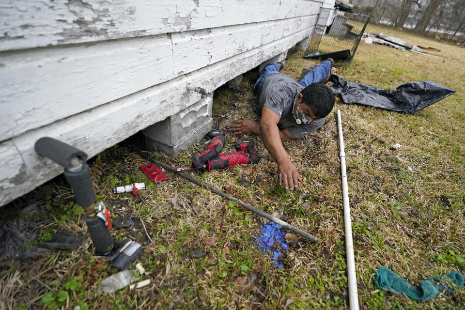 Martin Uribe, with West Street Recovery, works to repair busted pipes under a home, that were frozen during a recent winter storm, Thursday, Feb. 25, 2021, in Houston. West Street Recovery, a nonprofit created in the wake of Hurricane Harvey to help repair flood damaged homes, has been working since the winter storm hit to repair and replace damaged plumbing systems for residents who can't afford to do so. (AP Photo/David J. Phillip)