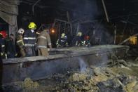 Ukrainian State Emergency Service firefighters to take away debris at a shopping center burned after a rocket attack in Kremenchuk, Ukraine, early Tuesday, June 28, 2022. (AP Photo/Efrem Lukatsky)