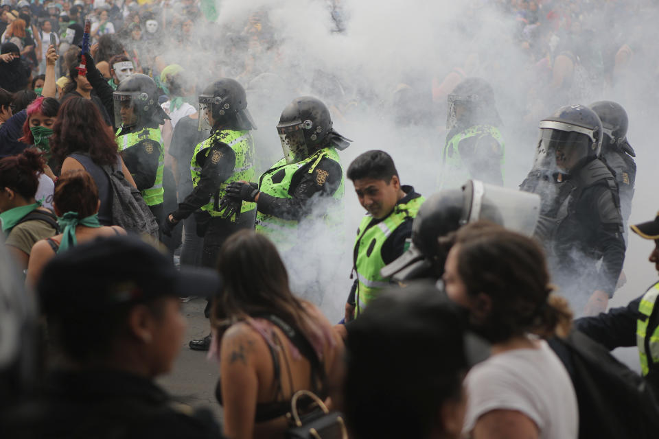 A cloud of smoke engulfs police after they put out a fire started by protesters during a women's rights protest in Mexico City, Saturday Sept. 28, 2019. Mexican women on Saturday marched for abortion rights, highlighting increased efforts across Latin America to lift some of the world's most restrictive abortion laws. (AP Photo/Anthony Vazquez)