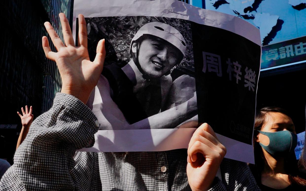 Protesters hold a photo of Chow Tsz-Lok during a memorial flash mob to remember him in Hong Kong - AP