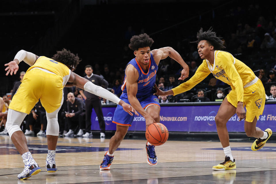 Florida guard Zyon Pullin (0) drives between Pittsburgh guard Carlton Carrington, right, and forward Blake Hinson during the second half of an NCAA college basketball game in the NIT Season Tip-Off on Wednesday, Nov. 22, 2023, in New York. (AP Photo/Eduardo Munoz Alvarez)