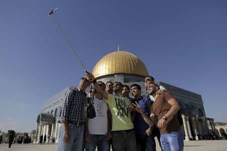 Palestinian Hakem Shtayeh (C), 28, from the West Bank city of Nablus, takes a selfie photo with friends in front of the Dome of the Rock on the compound known to Muslims as Noble Sanctuary and to Jews as Temple Mount, in Jerusalem's Old City, during the holy month of Ramadan, June 29, 2015. REUTERS/Ammar Awad