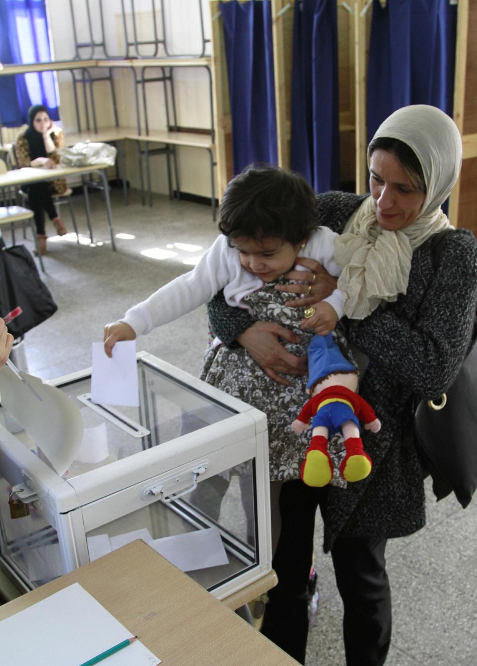 A mother allows her young daughter to cast her ballot for presidential elections in a polling station in downtown Algiers on April 17, 2014. Algerians headed to the polls to elect a president in a contest widely expected to be won by 77-year-old incumbent Abdelaziz Bouteflika who is running for a fourth term. (AP Photo/Paul Schemm)