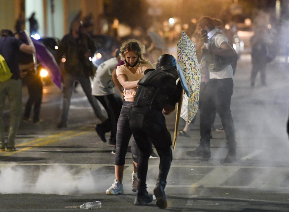 Protesters stand amid clouds of chemical irritant released by police outside the Public Safety Building in Rochester, N.Y., Thursday, Sept. 3, 2020. Seven police officers involved in the suffocation death of Daniel Prude in Rochester were suspended Thursday by the city's mayor, who said she was misled for months about the circumstances of the fatal encounter. (AP Photo/Adrian Kraus)