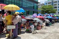 People line up outside a bank to withdraw cash, in Yangon