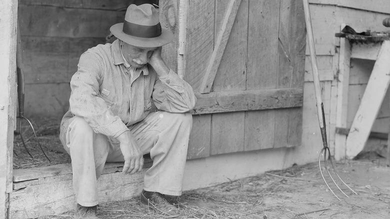 discouraged American farmer with pitchfork 1930s