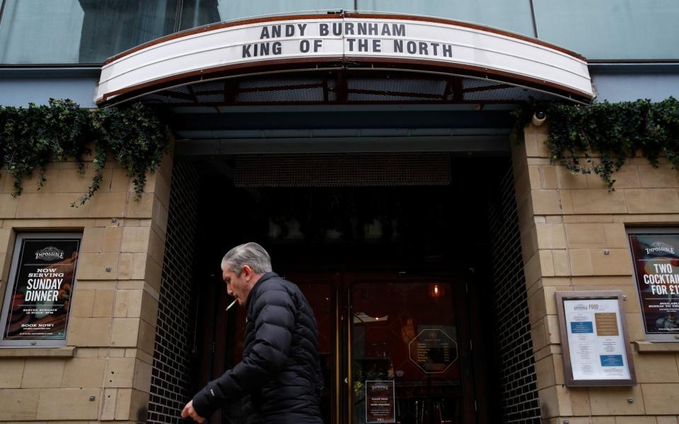 A man walks past a bar where a sign mentions Mayor of Manchester Andy Burnham, as the coronavirus disease outbreak continues - Phil Noble/Reuters