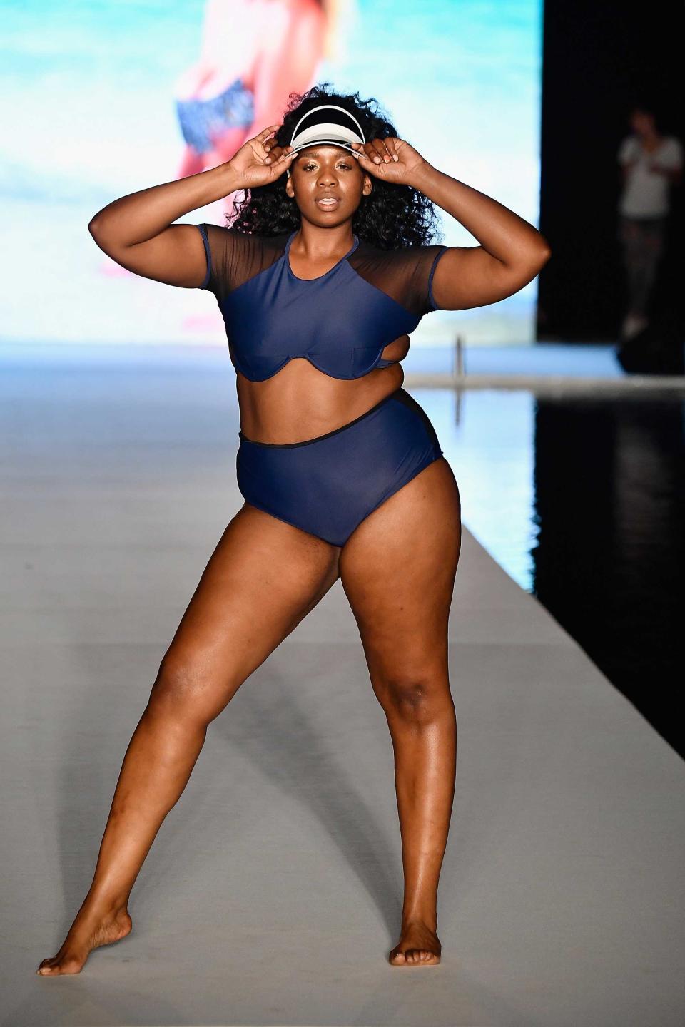 <p>A model walks the runway wearing a sporty navy sheer swimsuit and visor for the 2018 <em>Sports Illustrated </em>swimsuit show during the Paraiso Fashion Fair in Miami at the W South Beach hotel on July 15. (Photo: Alexander Tamargo/Getty Images for Sports Illustrated) </p>