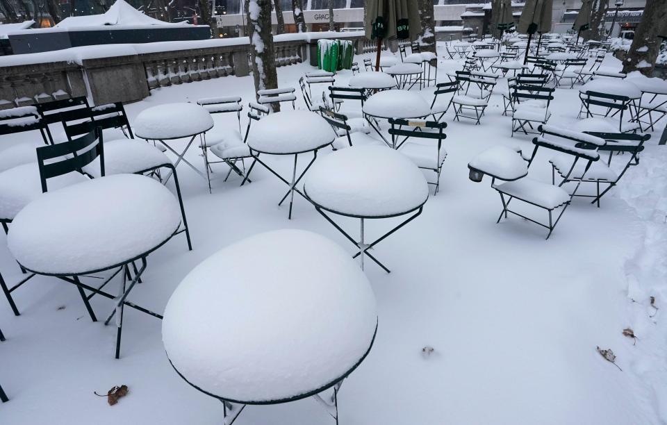 Tables and chairs are covered in snow at Bryant Park on December 17, 2020 in New York. / Credit: TIMOTHY A. CLARY/AFP via Getty