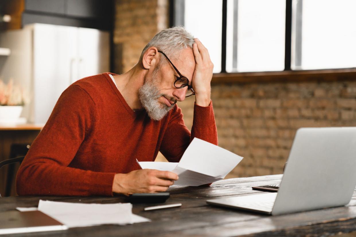 Expensive charges on domestic bills. Loan, debt, bunkruptcy concept. Sad depressed caucasian businessman holding documents, having problems with dismissal at home office