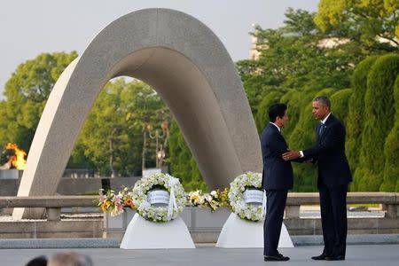 U.S. President Barack Obama (R) puts his arm around Japanese Prime Minister Shinzo Abe after they laid wreaths in front of a cenotaph at Hiroshima Peace Memorial Park in Hiroshima, Japan May 27, 2016. REUTERS/Carlos Barria