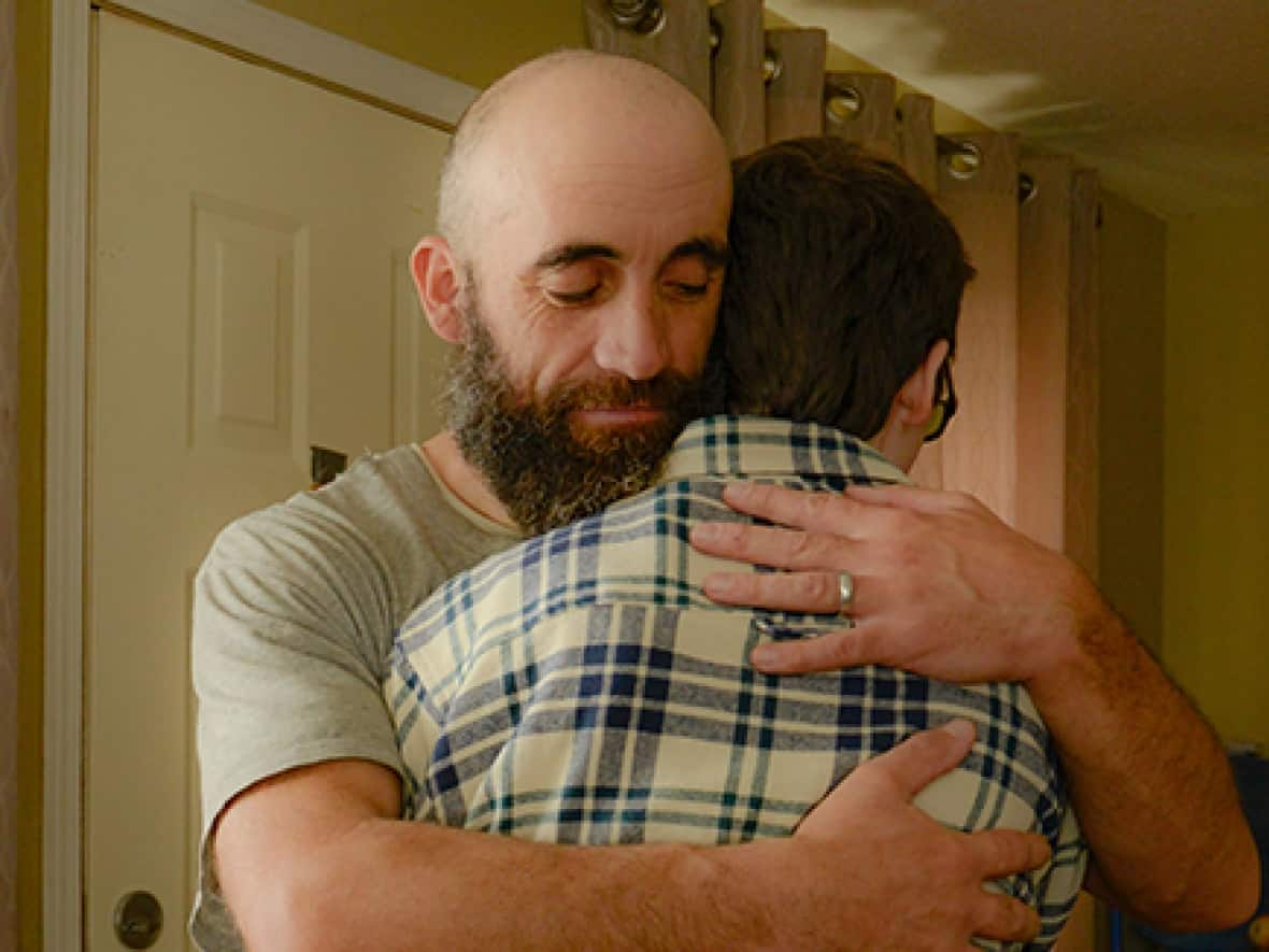 John Haslam hugs his son, Adam Tyrrell Haslam, in their motel room. Turning Point, a local outreach and shelter service, helped them get the room when the home they'd been renting was put up for sale, the family says. (Padraig Mac Roibeaird - image credit)