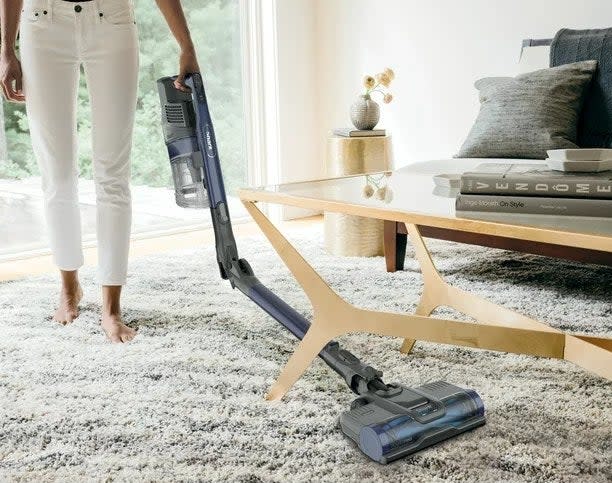 A model using the vacuum to clean under a coffee table