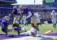 Washington wide receiver Ja'Lynn Polk, center top, falls after scoring a touchdown against Tulsa safety Kendarin Ray (1) during the first half of an NCAA college football game Saturday, Sept. 9, 2023, in Seattle. (AP Photo/Lindsey Wasson)