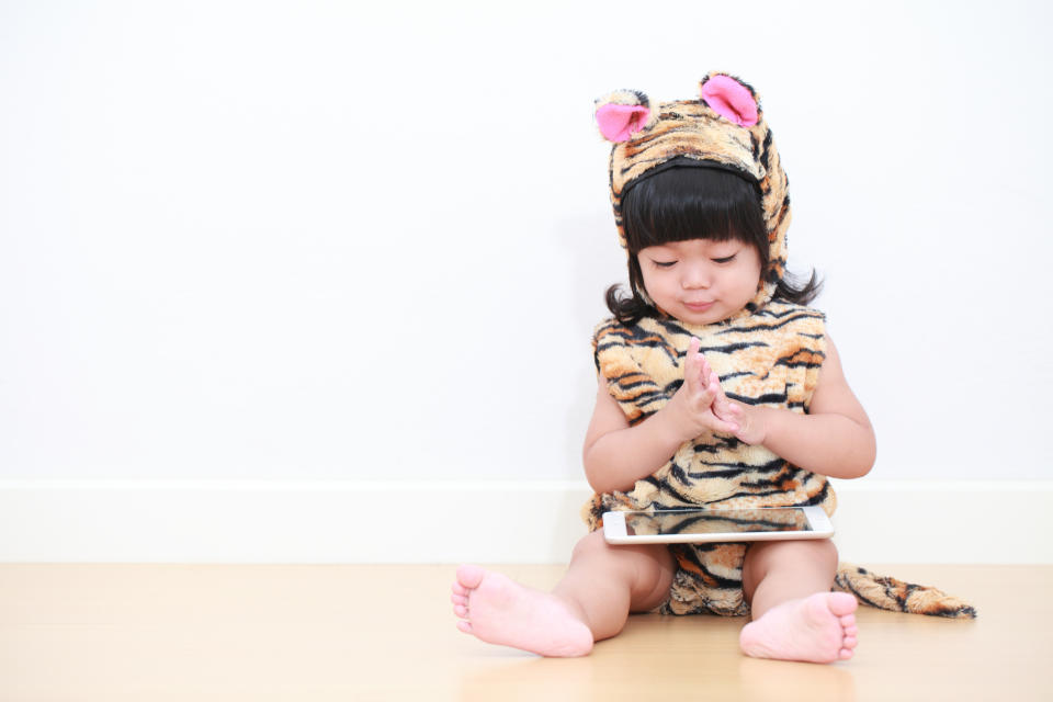 Portrait of baby girl playing tablet in white background. Photo: Getty Images.