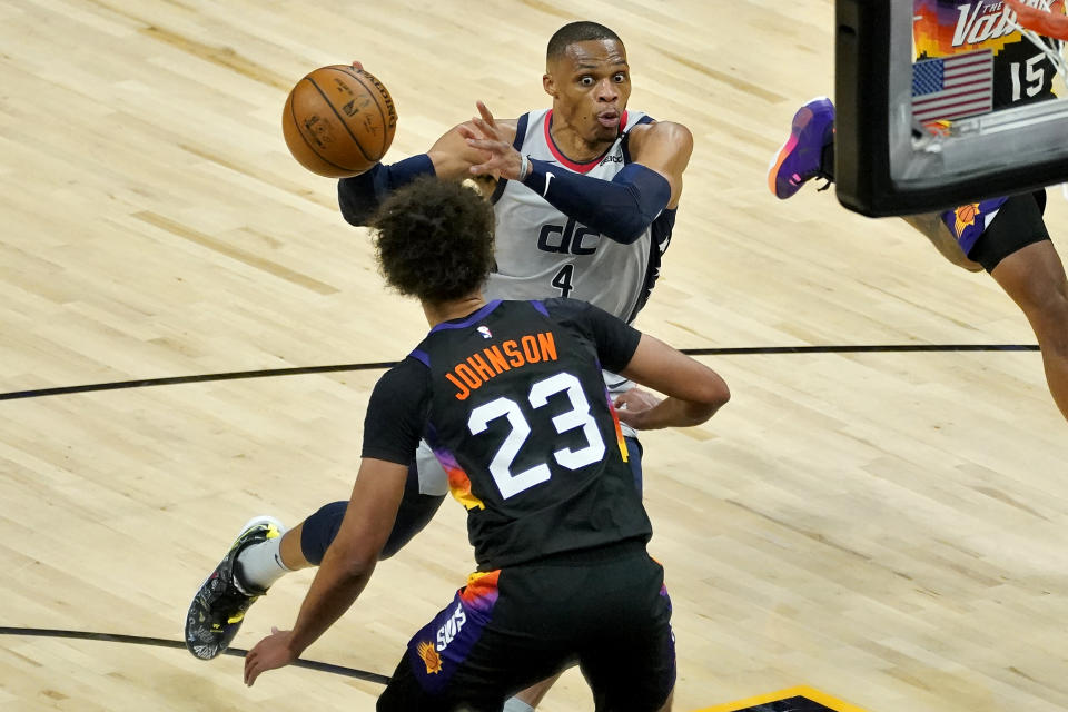 Washington Wizards guard Russell Westbrook (4) passes around Phoenix Suns forward Cameron Johnson (23) during the second half of an NBA basketball game, Saturday, April 10, 2021, in Phoenix. (AP Photo/Matt York)