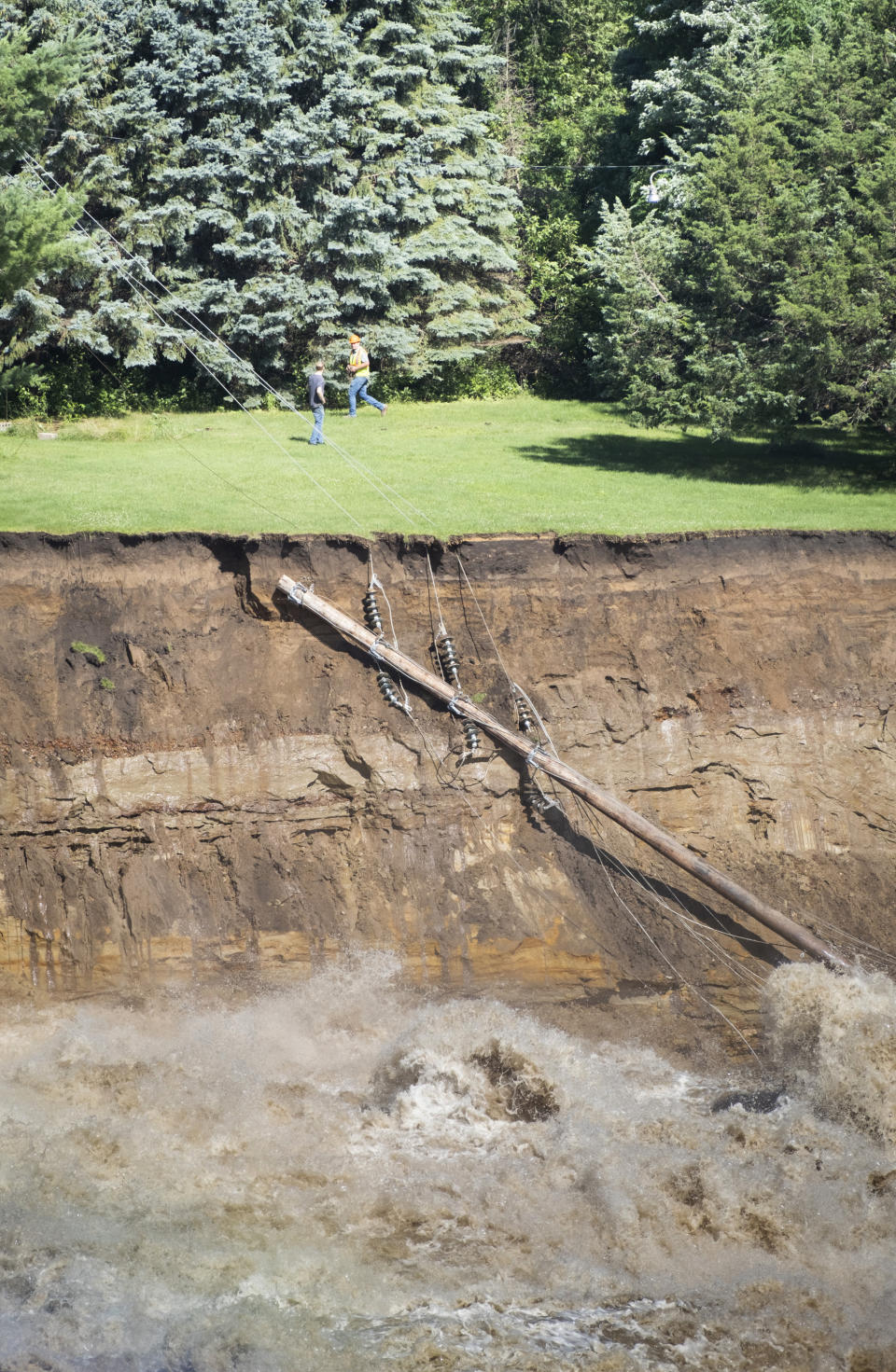 A utility pole dangles along the cliffs formed by the roaring waters of the Blue Earth River that subverted the Rapidan Dam, Monday, June 24, 2024, in Rapidan, Minn. (Casey Ek/The Free Press via AP)