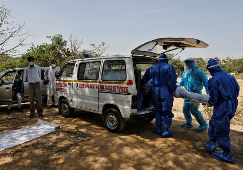 Trabajadores sanitarios llevan el cuerpo de un hombre que murió por la enfermedad del coronavirus (COVID-19), para su entierro en un cementerio de Nueva Delhi, India