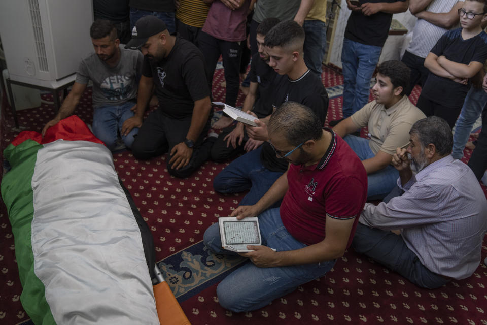 Mourners read versus of Quran and take the last look at the body of Salah Sawafta, 58 during his funeral at a mosque, in the West Bank city of Tubas, Friday, Aug. 19, 2022. Israeli forces shot and killed Sawafta during an arrest raid in the occupied West Bank on Friday, according to his brother, who said he was walking home when a bullet struck him in the head as Israeli forces clashed with Palestinian youths. (AP Photo/Nasser Nasser)