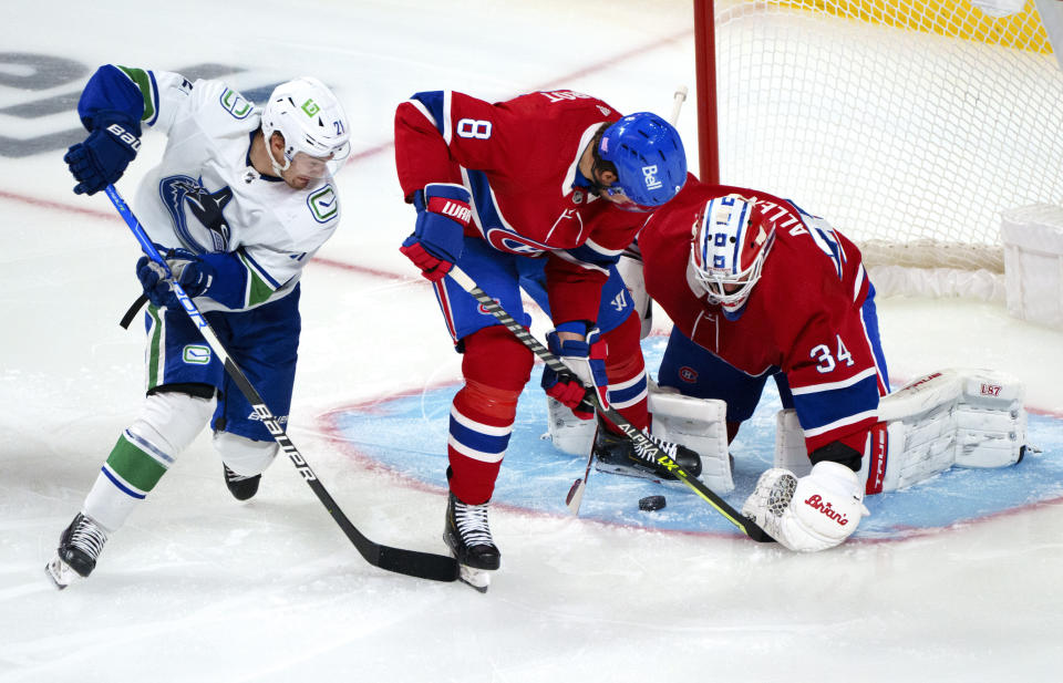 Montreal Canadiens goaltender Jake Allen and defenseman Ben Chiarot (8) shield the puck away from Vancouver Canucks' Nils Hoglander (21) during the first period of an NHL hockey game, Monday, Nov. 29, 2021 in Montreal. (Paul Chiasson/The Canadian Press via AP)
