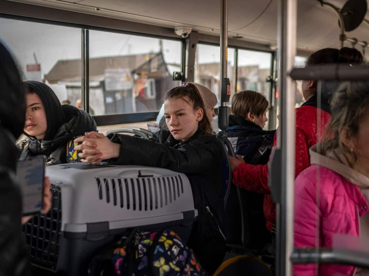 Ukrainian refugees sit on a shuttle bus after crossing the Ukrainian border with Poland at the Medyka border crossing, southeastern Poland, on March 27, 2022, following Russia's invasion of Ukraine.  (Angelos Tzortzinis/AFP/Getty Images - image credit)