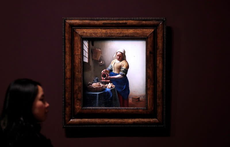 FILE PHOTO: An employee poses in front of the painting "The Milkmaid" (La laitiere, 1657-1658) by Dutch painter Johannes Vermeer at the Louvre museum in Paris