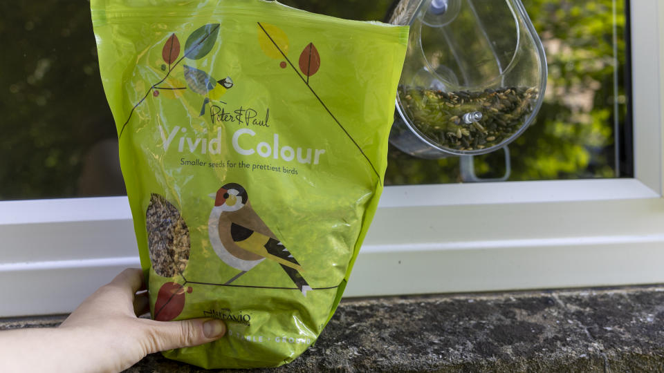 A female hand holding a bag of bird food