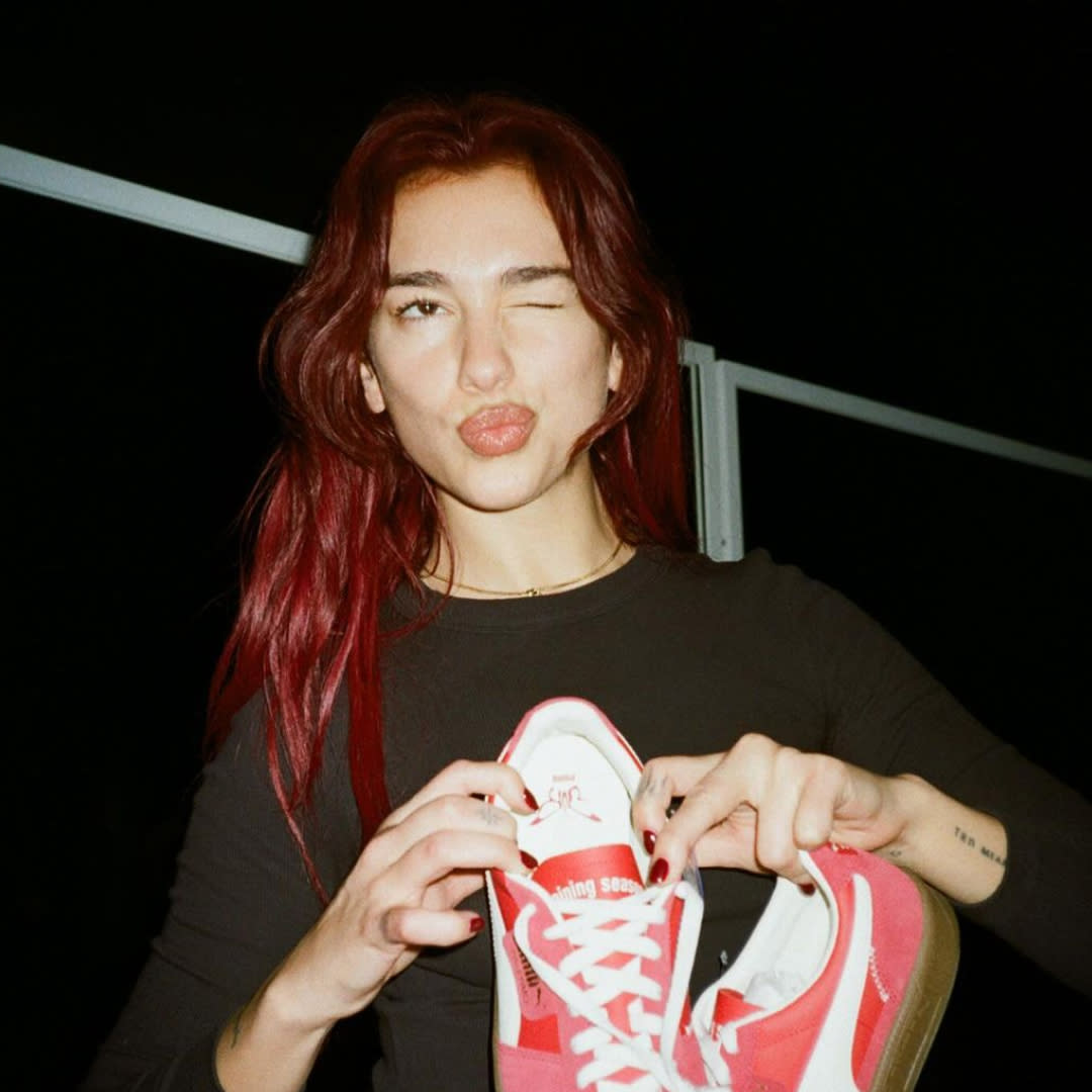  Dua Lipa holds up a pair of sneakers while rehearsing for an awards show. 