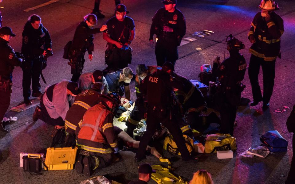 Emergency workers tend to one of the injured people on the ground after a driver sped through a protest-related closure on the Interstate 5 freeway in Seattle - James Anderson