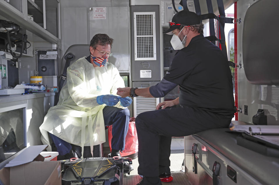 In this Saturday, May 9, 2020 photo, photographer Jason Vinlove, right, gets tested for COVID-19 antibodies before covering UFC 249 mixed martial arts event in Jacksonville, Fla.  There is no universal playbook for coronavirus testing in professional sports. Protocols and procedures, guidelines and handbooks, they could be as different as the rulebooks that govern leagues around the world. UFC performed nasal swabs and/or blood tests for roughly 1,200 people on site during its weeklong stay in Jacksonville, part of the mixed martial arts behemoth’s health and safety protocols. (AP Photo/John Raoux)