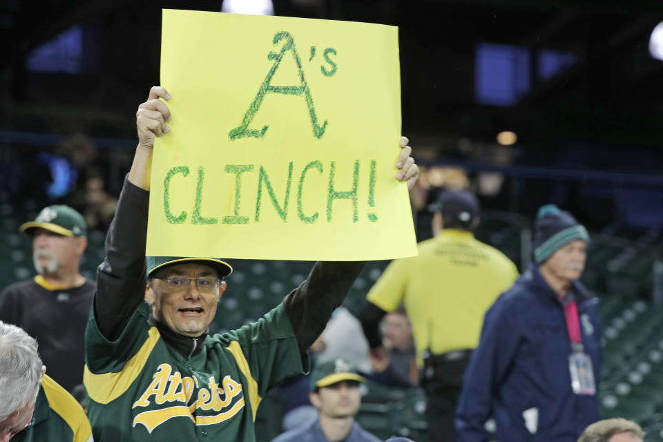 A fan holds a sign that reads "A's Clinch!" before a baseball game between the Seattle Mariners and the Oakland Athletics, Friday, Sept. 27, 2019, in Seattle. The Athletics clinched a wild-card berth in the American League before the first pitch of their game when the Cleveland Indians lost to the Washington Nationals. (AP Photo/Ted S. Warren)