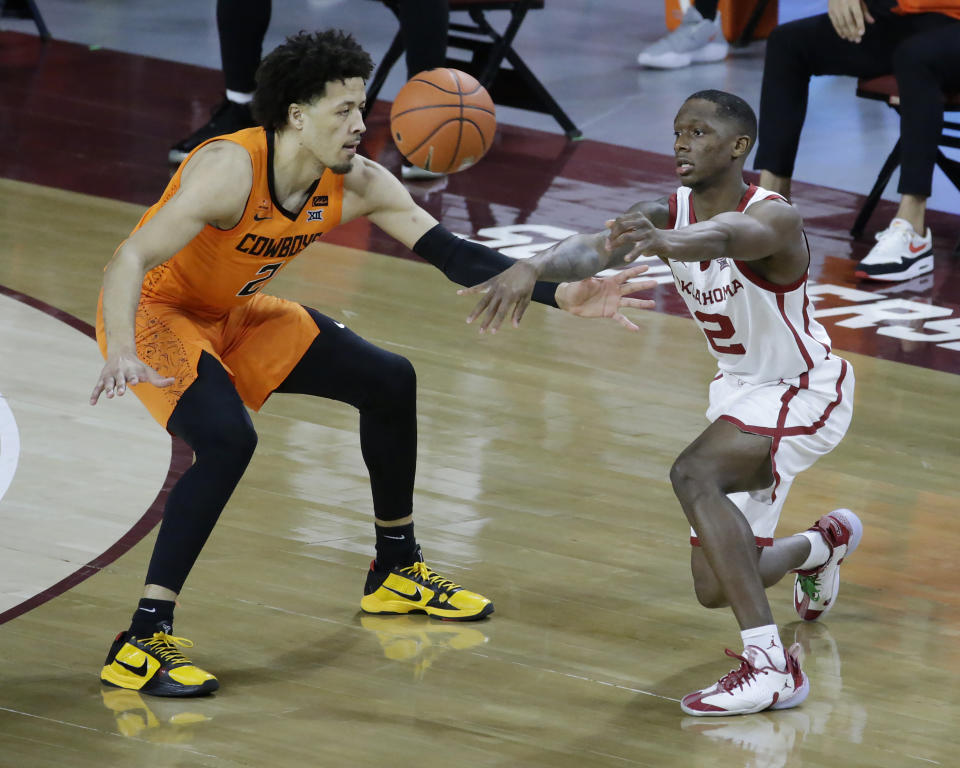 Oklahoma guard Umoja Gibson, right, passes the ball away from Oklahoma State guard Cade Cunningham, left, during the first half of an NCAA college basketball game, Saturday, Feb. 27, 2021, in Norman, Okla. (AP Photo/Garett Fisbeck)