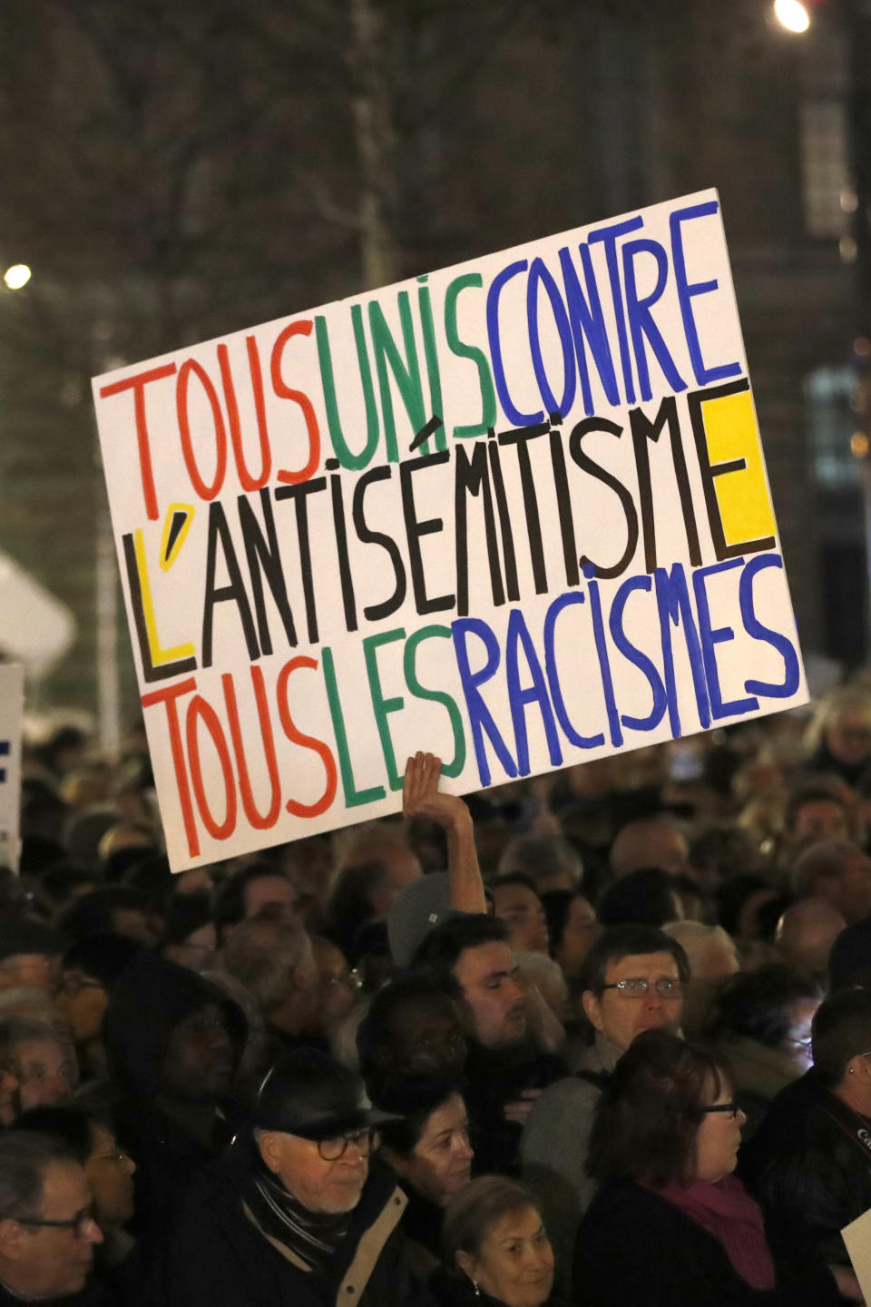 People gather at the Republique square to protest against anti-Semitism, in Paris, France, Tuesday, Feb. 19, 2019. Poster reads : All together against anti-Semitism and racism. In Paris and dozens of other French cities, ordinary citizens and officials across the political spectrum geared up Tuesday to march and rally against anti-Semitism, following a series of anti-Semitic acts that shocked the nation. (AP Photo/Christophe Ena)